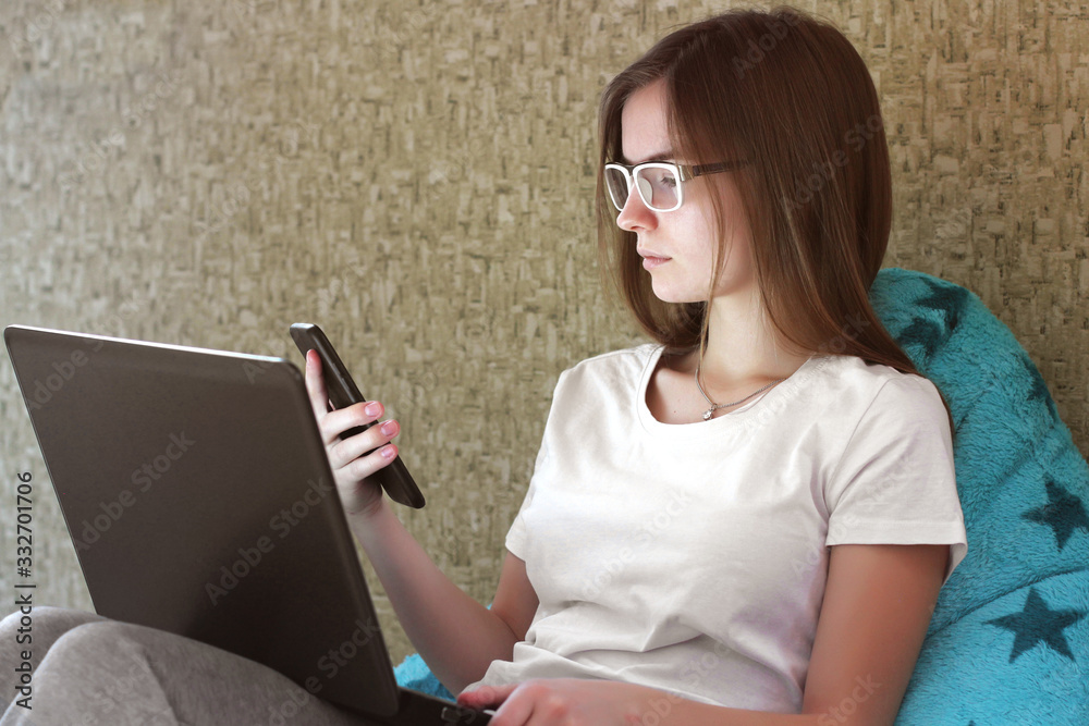 Girl with a phone and a computer. Freelance. Beautiful girl sitting on internet using smartphone. Girl works at home Girl with a phone and a computer. Freelance. Beautiful girl sitting on internet using smartphone. Girl works at home