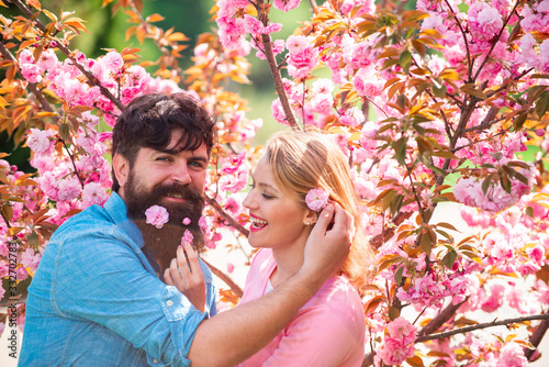 Lovers on a walk in a spring blooming park. Young happy couple in love outdoors. Spring portrait of beautiful happy couple. Romantic date couple concept.