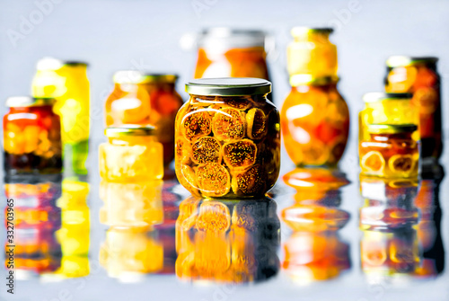 Dried fruits filled with honey and preserved in glass jars with metal lids on a light background.