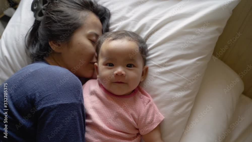 Asian little child lying in bed with their mother in the bedroom