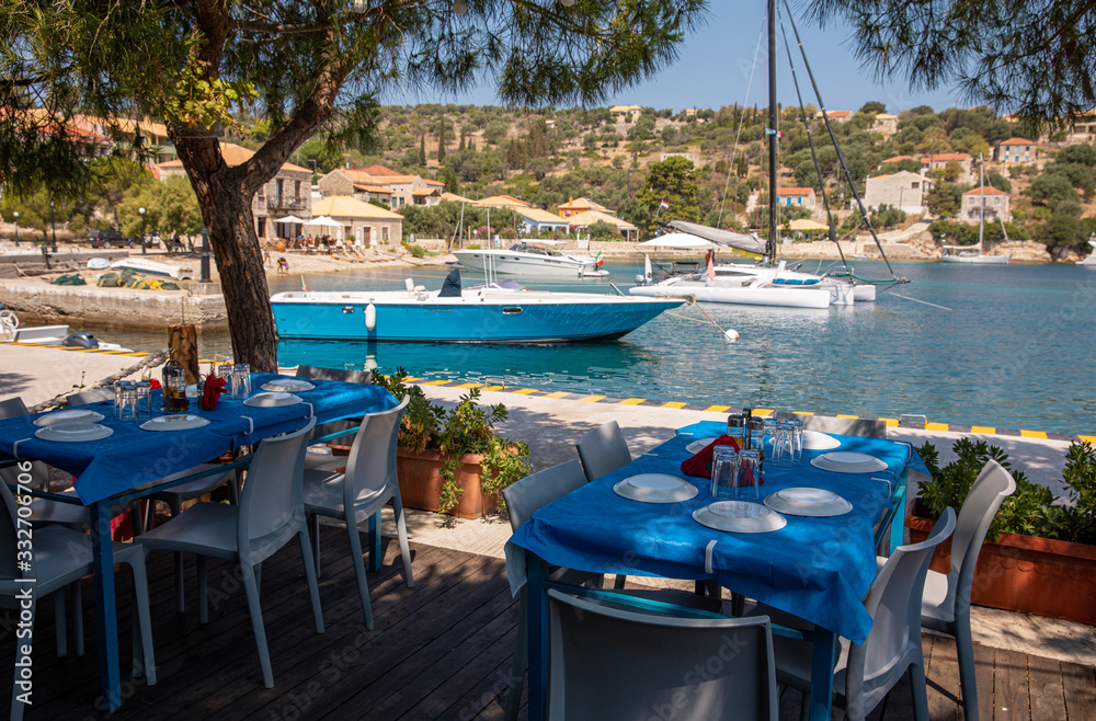 Fototapeta Traditional blue and white greek tavern with beautiful sea view on a summer sunny day in Kastos island, Lefkada Regional unit, Ionian Islands, Greece.