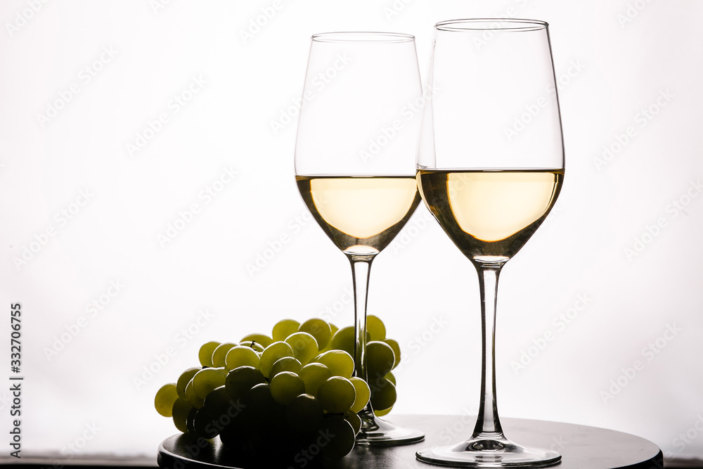 Two glasses with white wine and grapes on white background Two glasses with white wine and grapes on white background