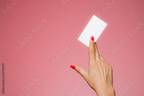 Woman's hand hold blank business card isolated on pink