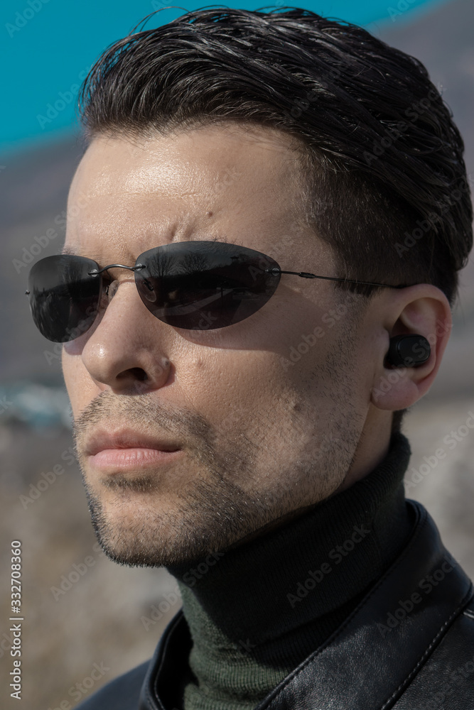 Portrait of a man with a smooth haircut and dark sunglasses looking like a  secret agent or character from the movie The Matrix Stock Photo | Adobe  Stock