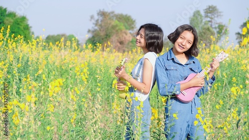 Happy ASian yoing girl play ukulele at flower field. photo