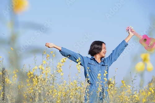 Happy ASian yoing girl play ukulele at flower field. photo