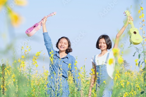 Happy ASian yoing girl play ukulele at flower field. photo