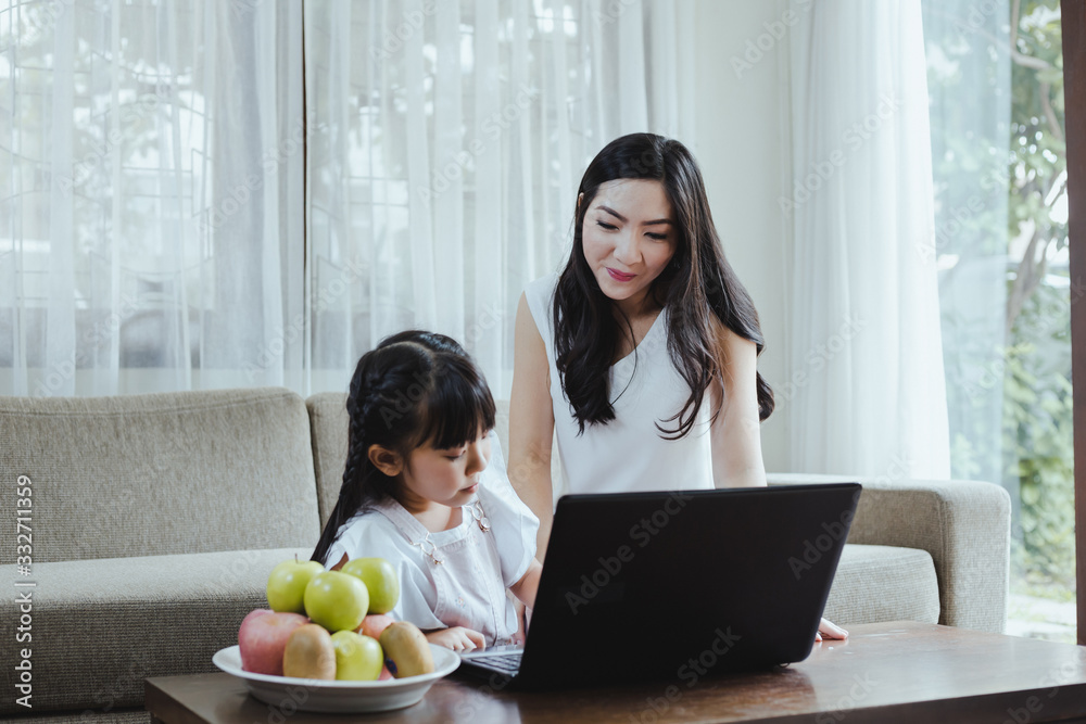Mother and daughter playing laptop together in the living room at home. Mother and daughter playing laptop together in the living room at home.