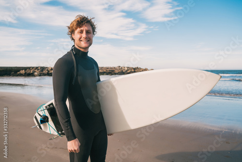 Surfer standing in the ocean with his surfboard.