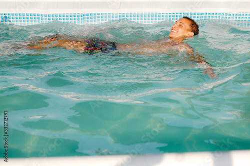 Boy is swimming on the water, floating, in the swimming pool