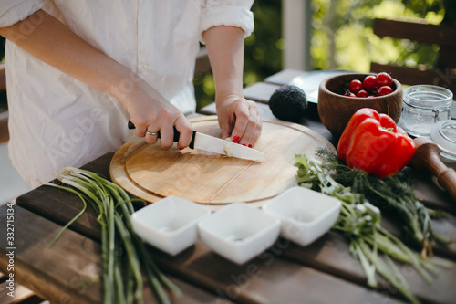 Woman's hands chopping garlic on wooden board. Cooking healthy food for picnic