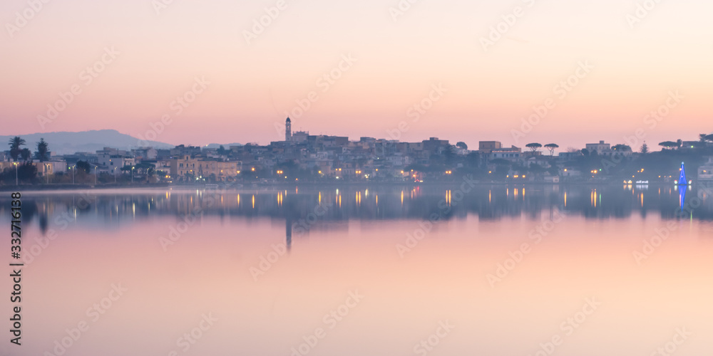 skyline all'alba di un paese italiano con riflessi sul lago