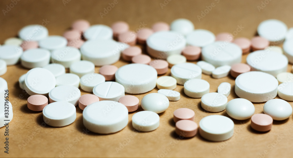 Heap of white pills, tablets, capsules on yellow orange background. Drug prescription for treatment medication health care concept wth copy space. Heap of white pills, tablets, capsules on yellow orange background. Drug prescription for treatment medication health care concept wth copy space.