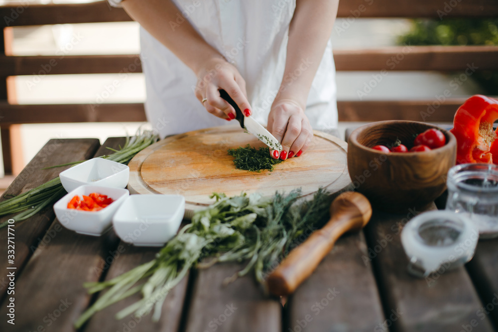 Woman's hands chopping dill on a wooden plate. Making guacamole Woman's hands chopping dill on a wooden plate. Making guacamole