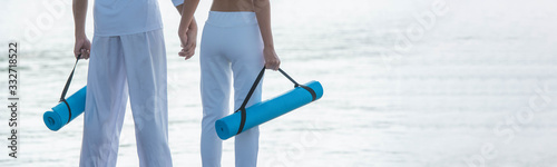 Young couple holding Yoga mat on water background with copy space for banner.