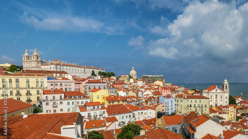 A big panorama of lisbon from a terrace. All the rooftops from above and the monastery of vincent and the santo estvao chruch at the back.