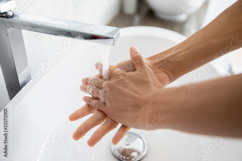 Close up female hands under running water in bathroom. After toilet woman wash her arms using antibacterial soap. Stop corona virus or 2019-ncov, good life habit, handwashing, personal hygiene concept