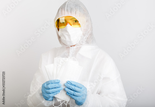doctor in anti-epidemic suit holds medical masks to protect against virus