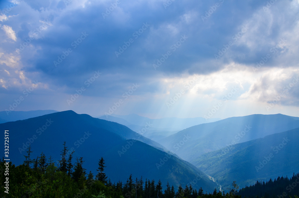 Clouds Above Sun Rays Shining on the Blue Carpathian Mountains on a cloudy fall evening in October Ukraine