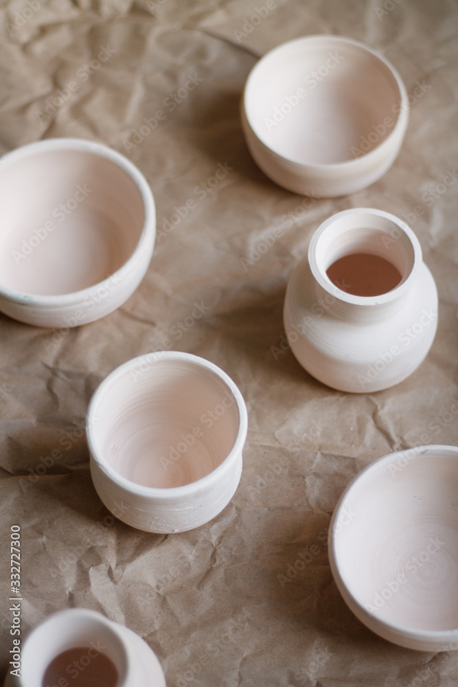 dishes made of white clay without glaze after firing on a brown background close-up. pottery dishes made of white clay without glaze after firing on a brown background close-up. pottery