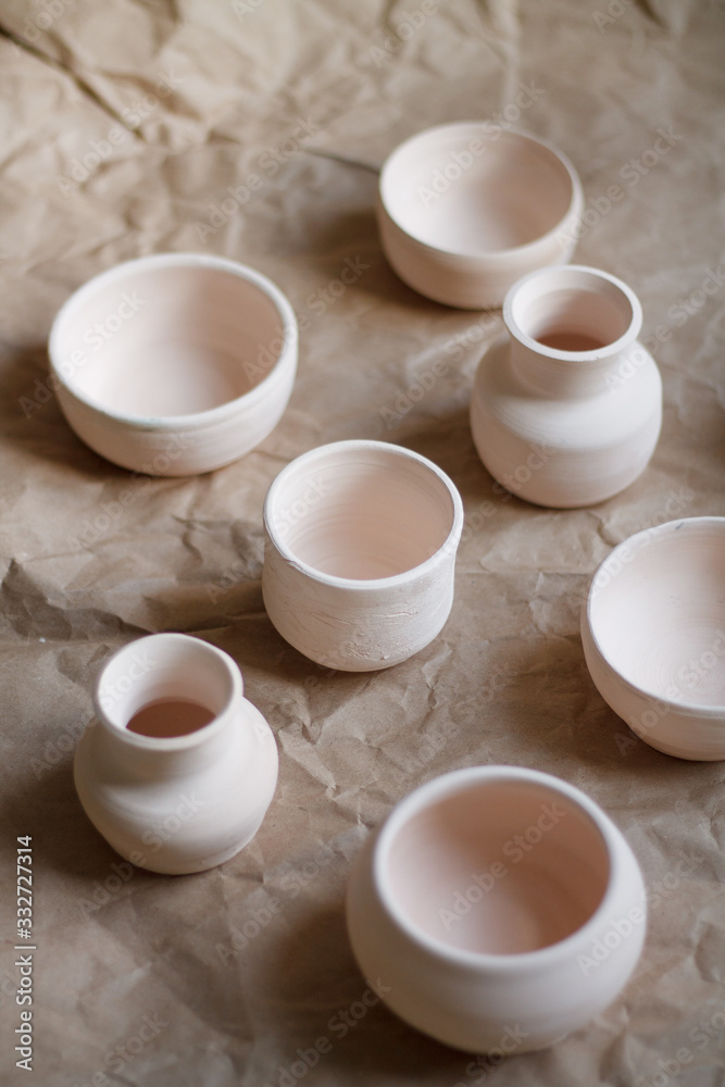 dishes made of white clay without glaze after firing on a brown background close-up. pottery dishes made of white clay without glaze after firing on a brown background close-up. pottery