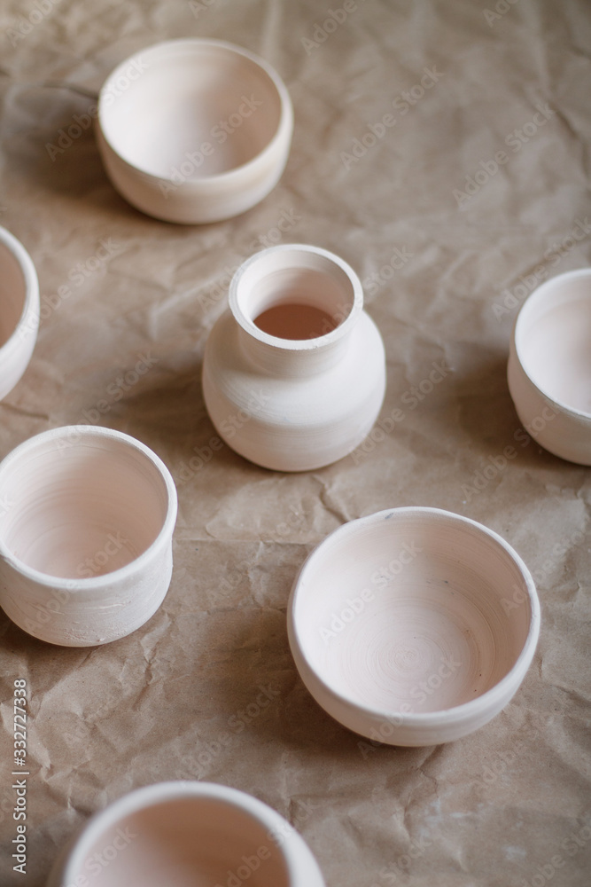 dishes made of white clay without glaze after firing on a brown background close-up. pottery dishes made of white clay without glaze after firing on a brown background close-up. pottery