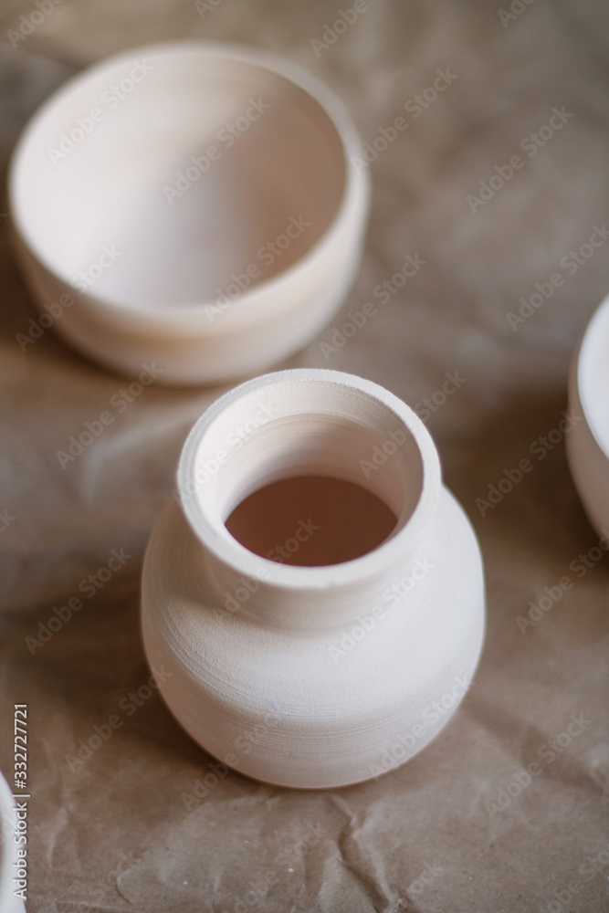 dishes made of white clay without glaze after firing on a brown background close-up. pottery dishes made of white clay without glaze after firing on a brown background close-up. pottery