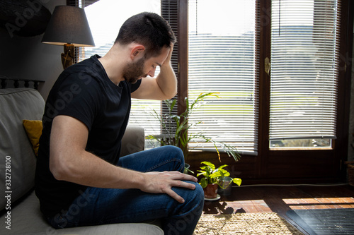 Young man with headache sitting on the couch