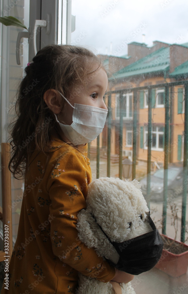 Ταπετσαρία A girl and a toy bear in medical masks near the window , looking at the street
