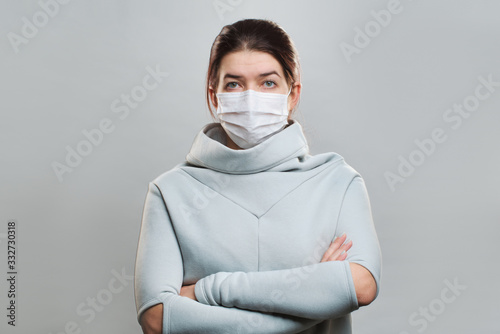 Young woman in medical mask with arms crossed isolated in studio © Sergey