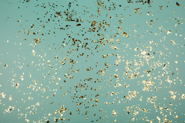 Golden flying sparkles on blue holiday background. Festive backdrop for your projects.