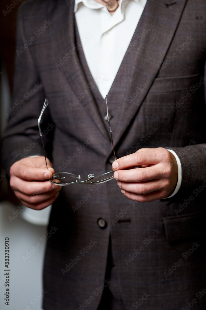 Man holds glasses. Attractive bearded young man in classic suit