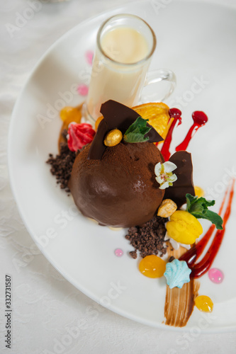 Elegant chocolate ice cream and fruit decorated with black chocolate, sauces, macaron and cream. Gourmet dessert