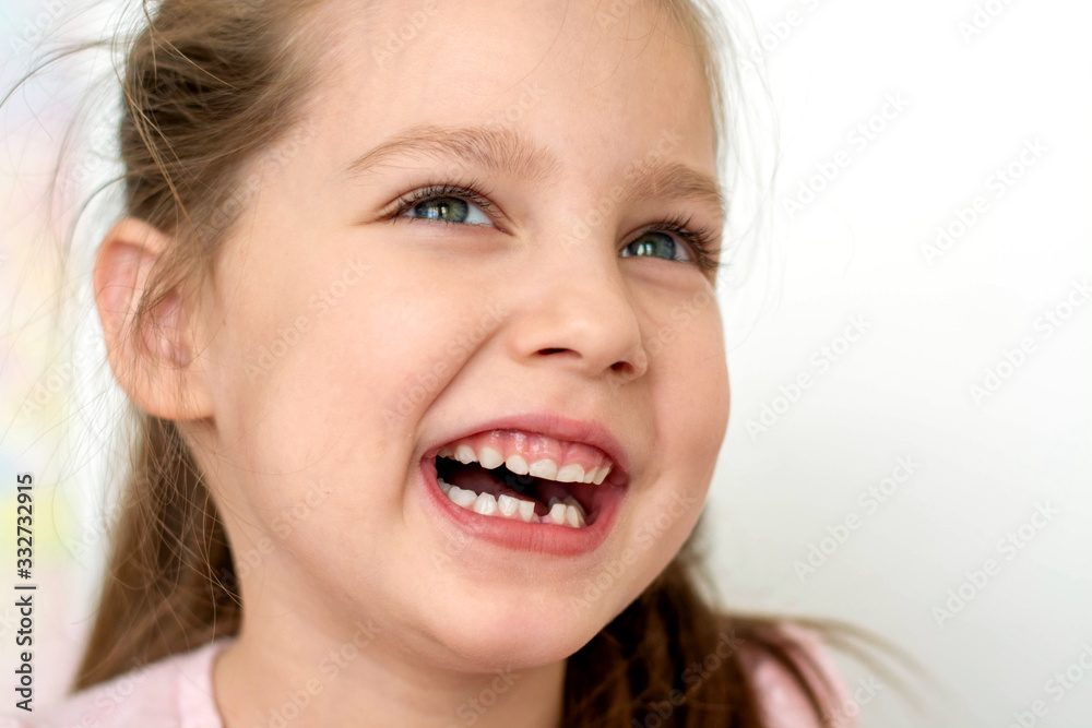 a happy girl in a pink school- age t-shirt without a front tooth laughs. To close. Diphyodont. Isolated on a white background. health a happy girl in a pink school- age t-shirt without a front tooth laughs. To close. Diphyodont. Isolated on a white background. health