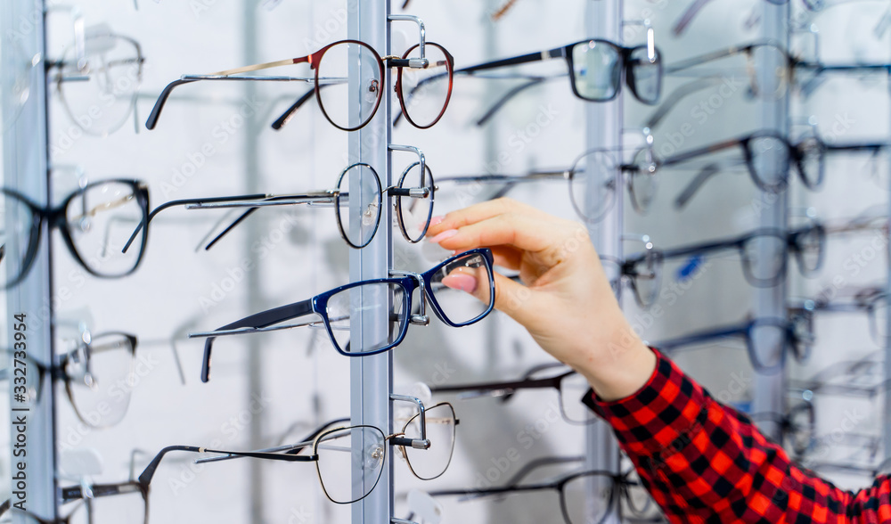 Woman choosing new pair of spectacles in opticians store. Optics. Ophthalmology. Woman choosing new pair of spectacles in opticians store. Optics. Ophthalmology.