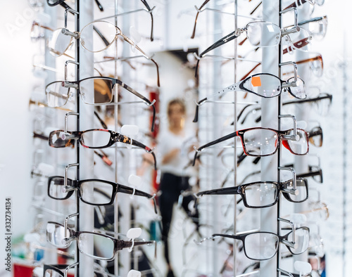 Optometrist, optician or eye doctor showing glasses on blurred background. Many eyeglasses in shop.