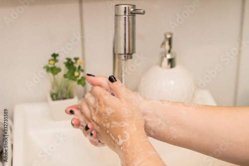 young woman washing her hands in the bathroom against coronavirus