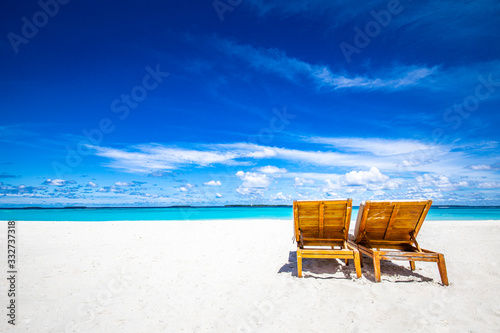 Fototapeta Naklejka Na Ścianę i Meble -  Tropical beach background as summer landscape with beach chairs beds over white sand and calm sea for beach banner. Perfect beach scene vacation and summer holiday concept. Boost up color process