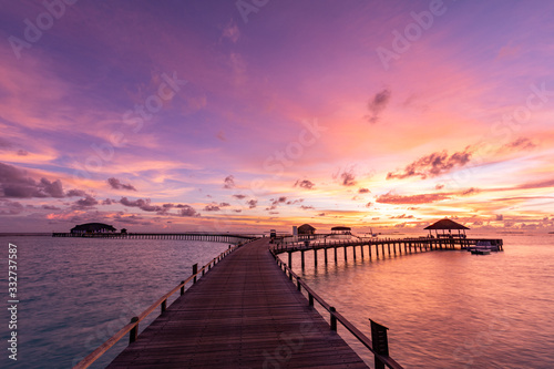 Sunset on Maldives island, luxury water bungalows villas resort and wooden pier. Beautiful sky and clouds and beach with seascape for summer vacation holiday and travel concept © icemanphotos