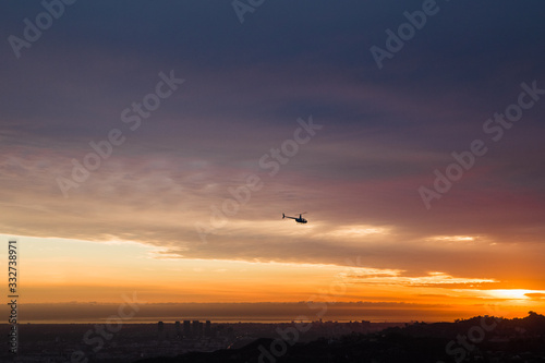 helicopter flies above city at sunset © Attila Adam