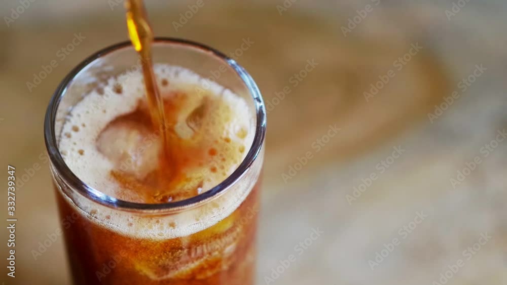 pouring cola into a glass with ice pouring cola into a glass with ice