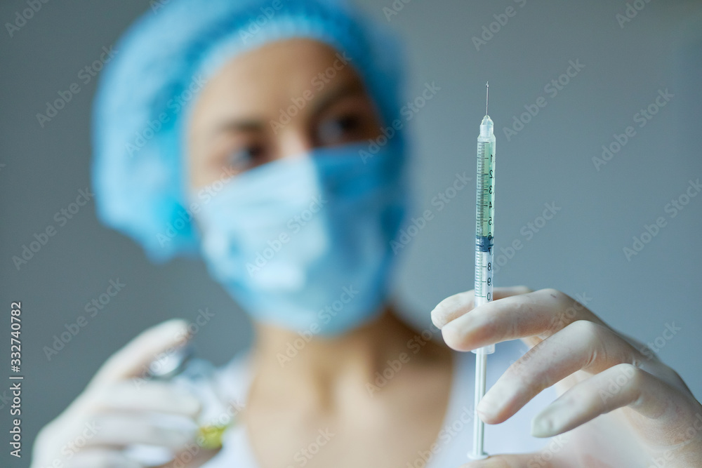 Syringe, vaccine, medical injection, bottle in hands in gloves. Woman doctor blurred on background. Syringe, vaccine, medical injection, bottle in hands in gloves. Woman doctor blurred on background.