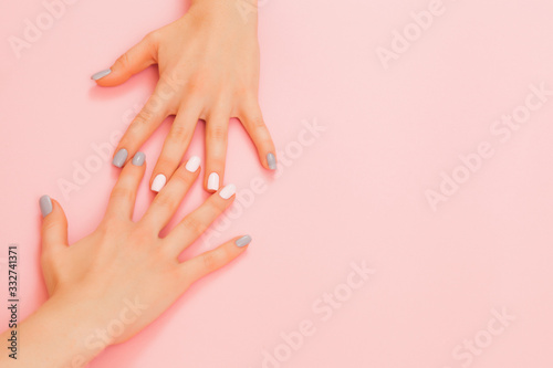 Hands of a beautiful woman on a pink background. Delicate hands with natural manicure, clean skin. Light blue grey nails.