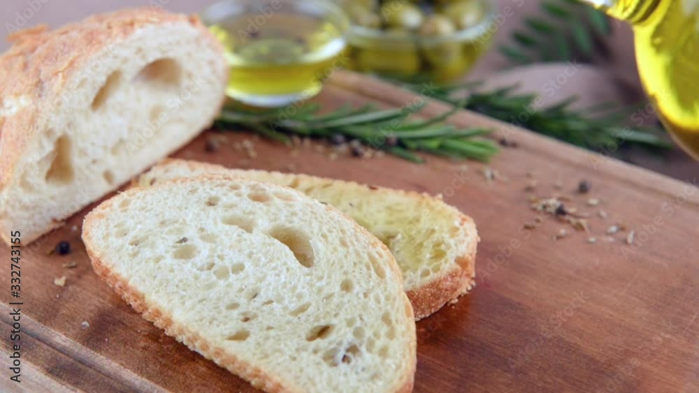 Pouring of fresh sliced bread with olive oil on table Pouring of fresh sliced bread with olive oil on table