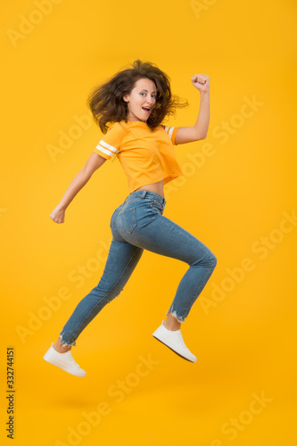 Feel inner energy. Energetic woman running or jumping. Skinny jeans suits her. Sexy girl yellow background. Sensual girl in casual style. Pretty girl with long hair. Fashion style. Beauty and make up