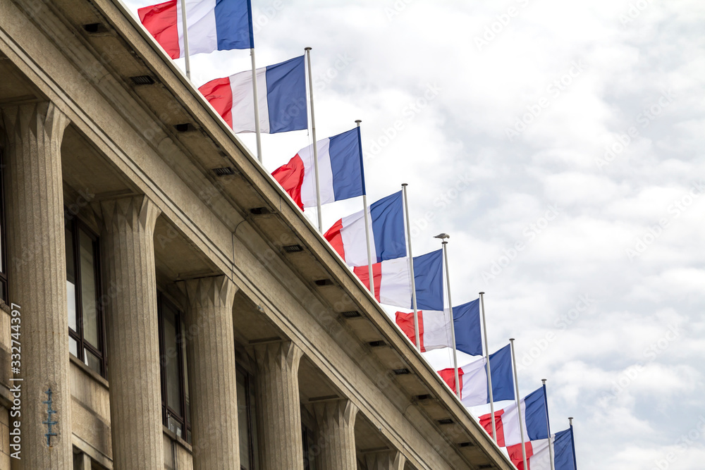 Closeup of a row of french flags waving on a roof top