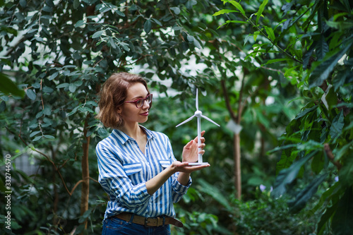 Foto Young woman standing in botanical garden, holding windmill model.