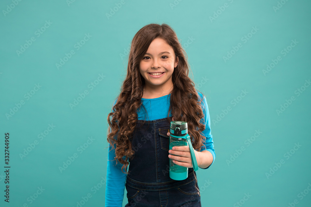 Drink some liquids. Water balance concept. Strong and healthy child. Living healthy life. Health and water balance. Girl hold water bottle blue background. Kid girl long hair has water bottle Drink some liquids. Water balance concept. Strong and healthy child. Living healthy life. Health and water balance. Girl hold water bottle blue background. Kid girl long hair has water bottle