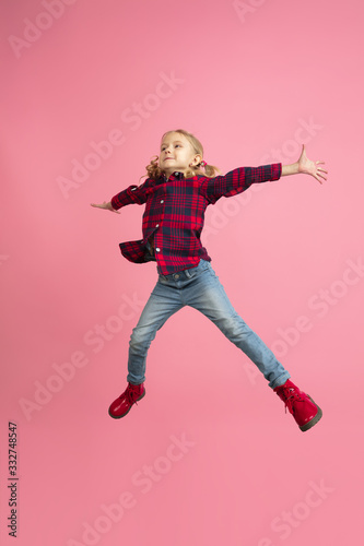 Free and happy, flying, jumping high. Caucasian girl's portrait on pink studio background. Beautiful model with blonde hair. Concept of human emotions, facial expression, sales, ad, youth, childhood.