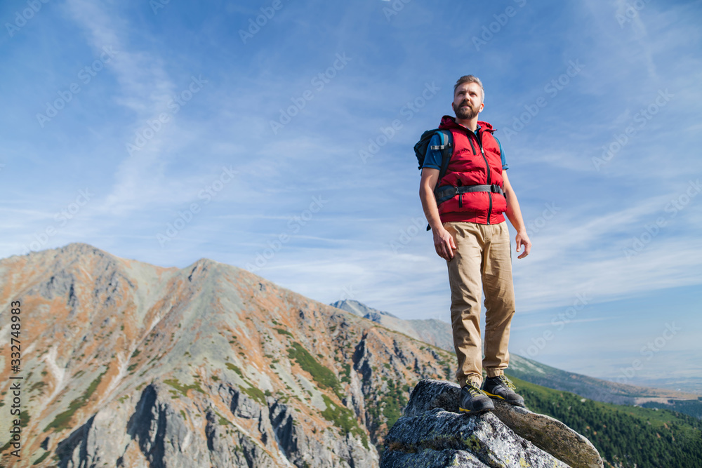 Naklejka premium Mature man with backpack hiking in mountains in summer.